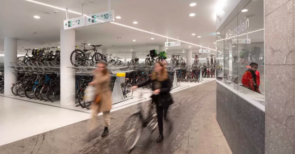 People entering the garage with a bike, displays showing available parking spaces 