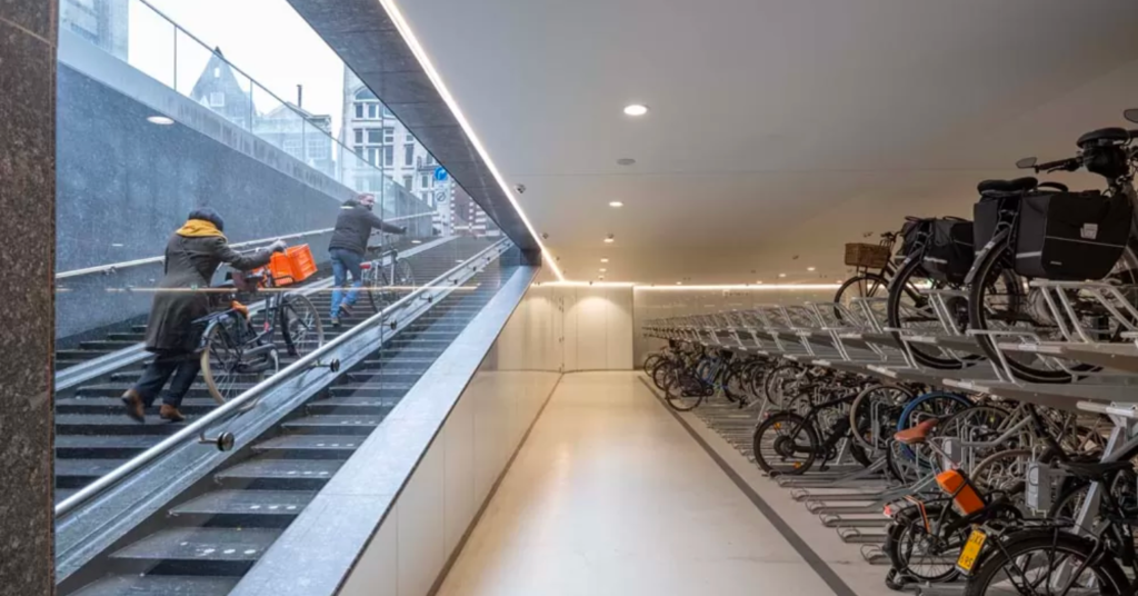 People coming out of the garage with their bikes using escalators 